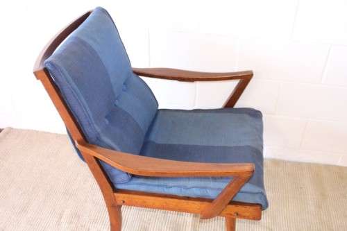 A fabulous mid-century solid teak armchair with sprung seat and backrest and blue fabric cushions