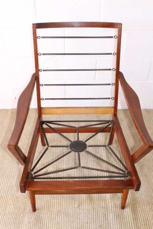A fabulous mid-century solid teak armchair with sprung seat and backrest and blue fabric cushions