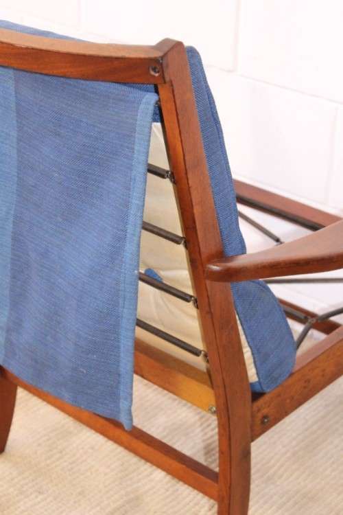 A fabulous mid-century solid teak armchair with sprung seat and backrest and blue fabric cushions
