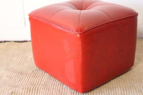 A beautiful, comfy red ottoman with a leather-like upholstery - perfect addition to a living room