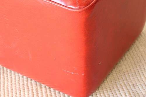 A beautiful, comfy red ottoman with a leather-like upholstery - perfect addition to a living room