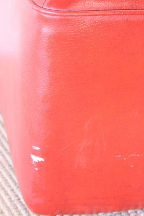 A beautiful, comfy red ottoman with a leather-like upholstery - perfect addition to a living room