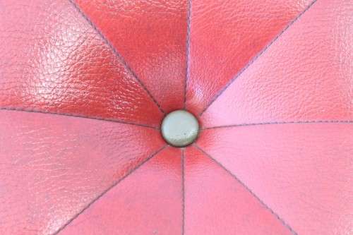 A beautiful, comfy red ottoman with a leather-like upholstery - perfect addition to a living room