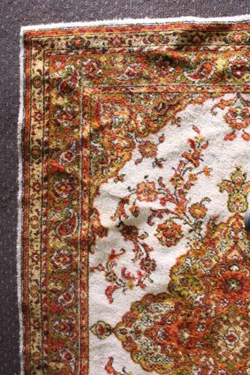 A vintage 189cm x 132cm Persian styled carpet w/ dark greens, marigold yellow, rust & earthy colours