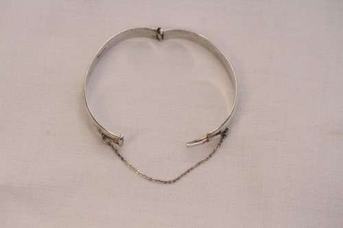 A beautiful vintage hinged sterling silver bangle with floral engraved detailing and a safety chain