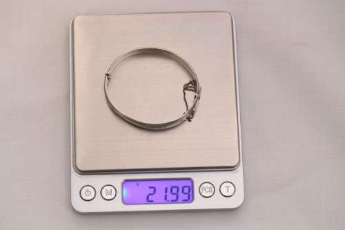 A beautiful vintage hinged sterling silver bangle with floral engraved detailing and a safety chain