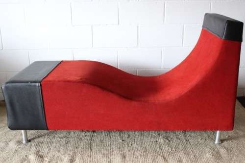 A modern styled black faux leather and red fabric chaise sofa with brushed metal legs