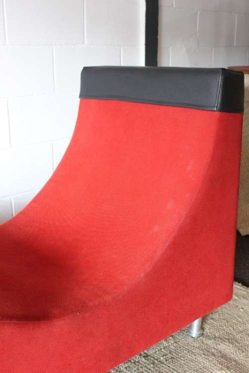 A modern styled black faux leather and red fabric chaise sofa with brushed metal legs