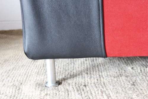 A modern styled black faux leather and red fabric chaise sofa with brushed metal legs