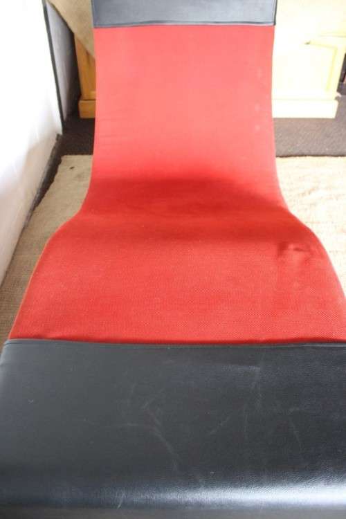 A modern styled black faux leather and red fabric chaise sofa with brushed metal legs