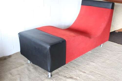A modern styled black faux leather and red fabric chaise sofa with brushed metal legs