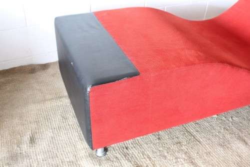 A modern styled black faux leather and red fabric chaise sofa with brushed metal legs