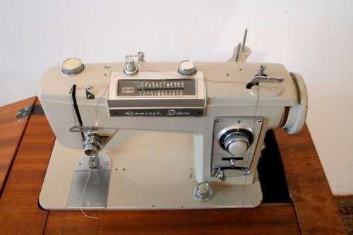 A vintage Empisal deluxe electric sewing machine in its original cabinet w/ accessories, working.