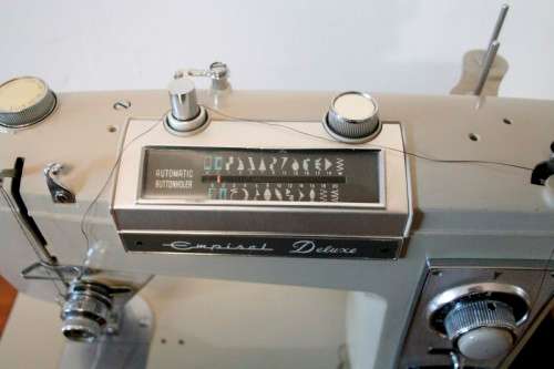 A vintage Empisal deluxe electric sewing machine in its original cabinet w/ accessories, working.
