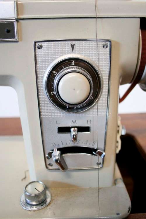 A vintage Empisal deluxe electric sewing machine in its original cabinet w/ accessories, working.