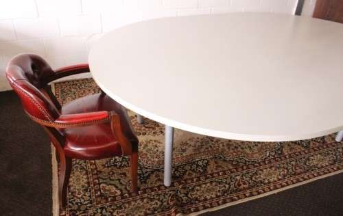A large oval modern styled, grey painted 8 to 10-seater boardroom table on a sturdy metal frame
