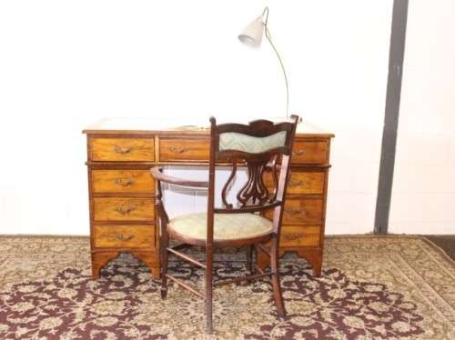 A beautiful vintage knee-hole writing desk w/ an off-white leather top & 9x drawers w/ brass handles
