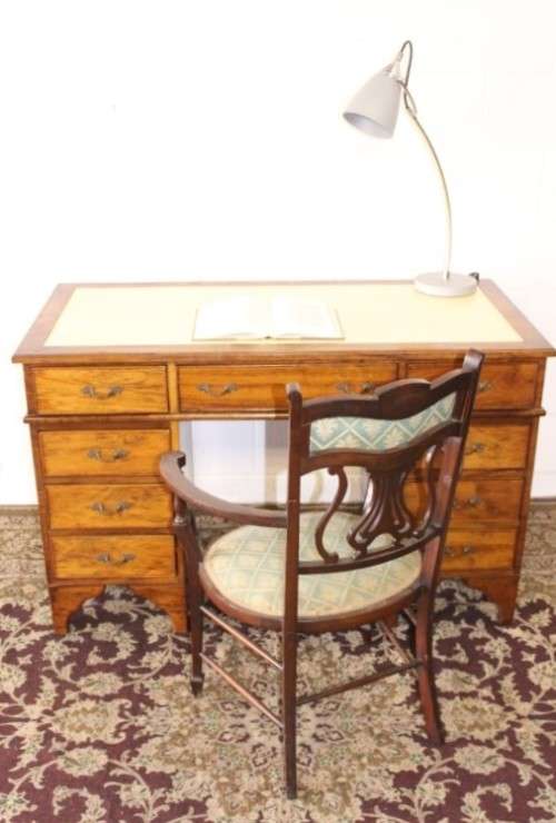 A beautiful vintage knee-hole writing desk w/ an off-white leather top & 9x drawers w/ brass handles