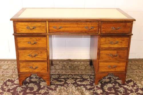 A beautiful vintage knee-hole writing desk w/ an off-white leather top & 9x drawers w/ brass handles