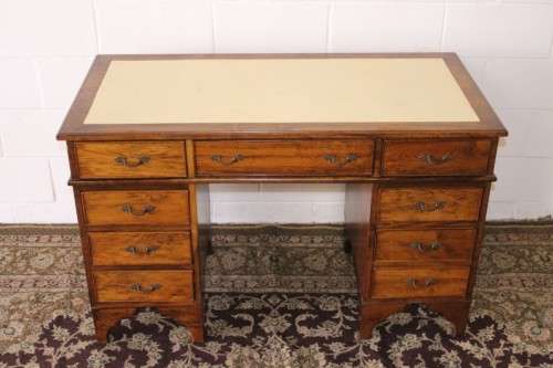 A beautiful vintage knee-hole writing desk w/ an off-white leather top & 9x drawers w/ brass handles