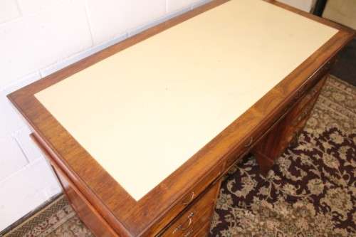 A beautiful vintage knee-hole writing desk w/ an off-white leather top & 9x drawers w/ brass handles