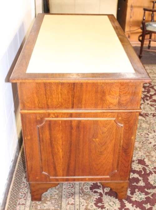 A beautiful vintage knee-hole writing desk w/ an off-white leather top & 9x drawers w/ brass handles