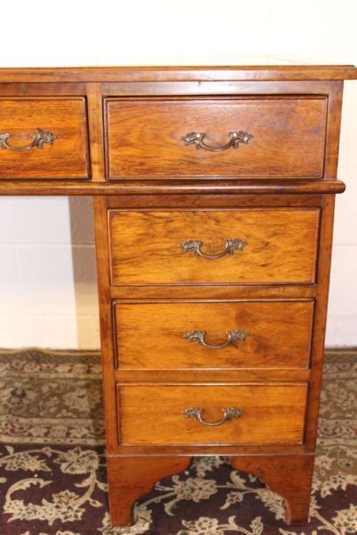A beautiful vintage knee-hole writing desk w/ an off-white leather top & 9x drawers w/ brass handles