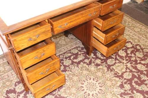 A beautiful vintage knee-hole writing desk w/ an off-white leather top & 9x drawers w/ brass handles