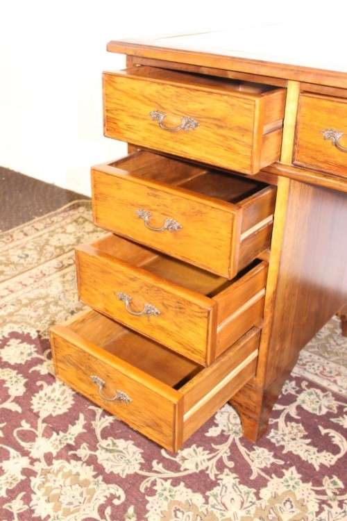 A beautiful vintage knee-hole writing desk w/ an off-white leather top & 9x drawers w/ brass handles
