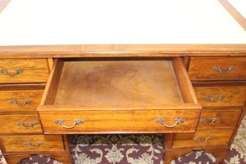 A beautiful vintage knee-hole writing desk w/ an off-white leather top & 9x drawers w/ brass handles