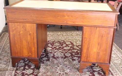 A beautiful vintage knee-hole writing desk w/ an off-white leather top & 9x drawers w/ brass handles