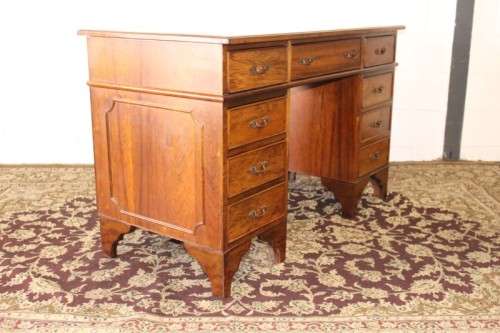 A beautiful vintage knee-hole writing desk w/ an off-white leather top & 9x drawers w/ brass handles