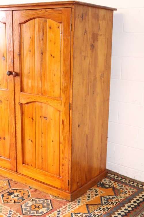 A solidly made double door SA pine storage cabinet with an array of shelves and storage space