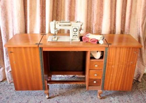 A vintage Empisal deluxe electric sewing machine in its original cabinet w/ accessories, working.