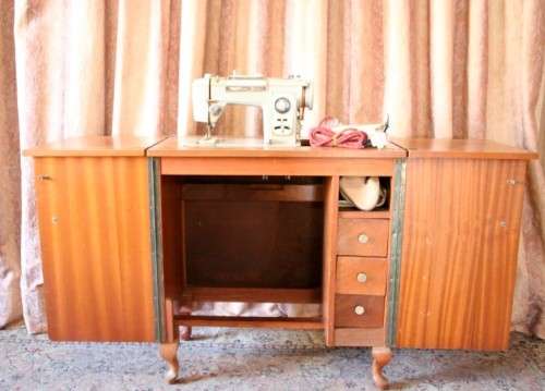 A vintage Empisal deluxe electric sewing machine in its original cabinet w/ accessories, working.