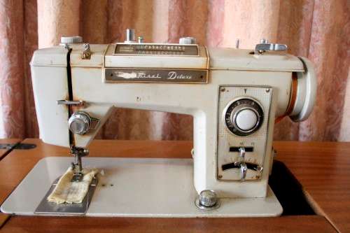 A vintage Empisal deluxe electric sewing machine in its original cabinet w/ accessories, working.