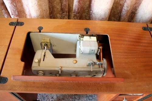 A vintage Empisal deluxe electric sewing machine in its original cabinet w/ accessories, working.