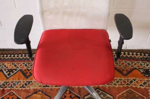 A modern styled red and white office chair with tilt, height and tension adjusters