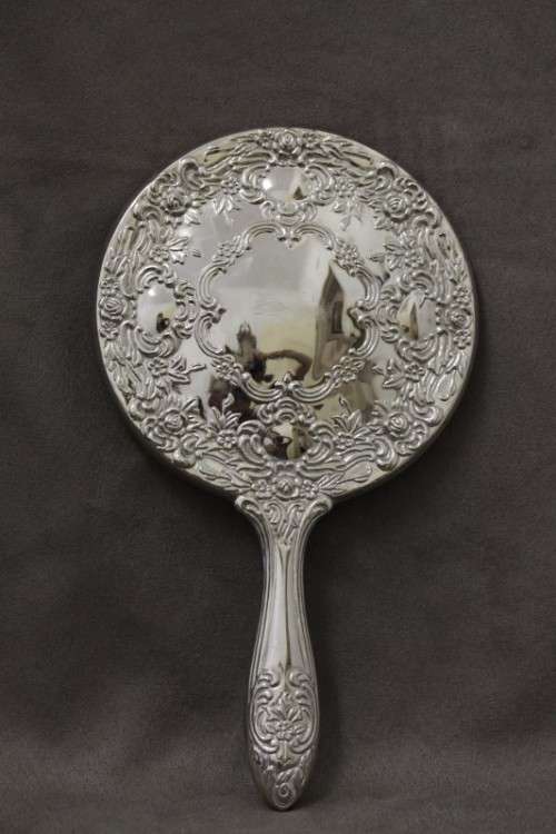 A beautiful, vintage ladies round chrome hand held vanity mirror with lovely detailing on the back.