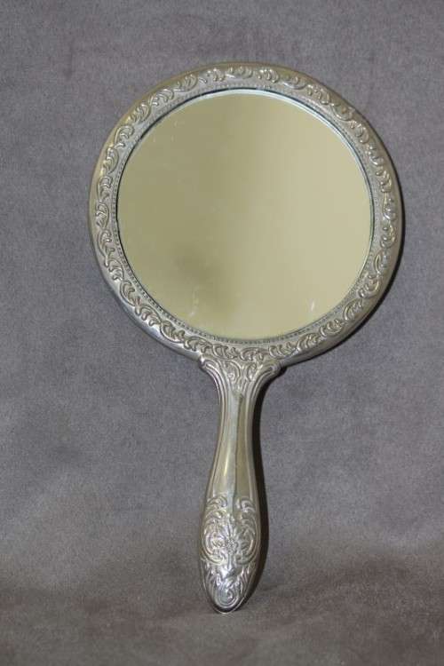 A beautiful, vintage ladies round chrome hand held vanity mirror with lovely detailing on the back.