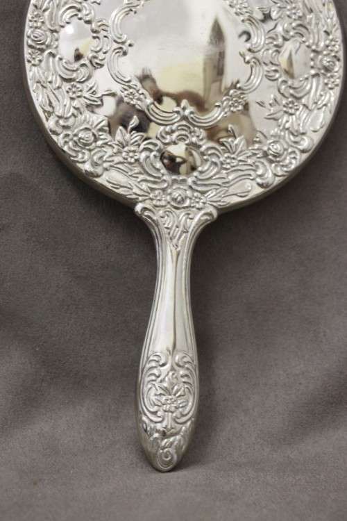 A beautiful, vintage ladies round chrome hand held vanity mirror with lovely detailing on the back.