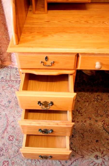 An exquisite Oak roll-top writing bureau with nine drawers, brass handles and pigeon holes.
