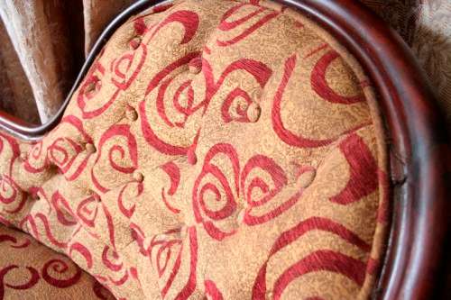An antique Victorian  "parlour settee" couch w carved detailing and period upholstery on castors.