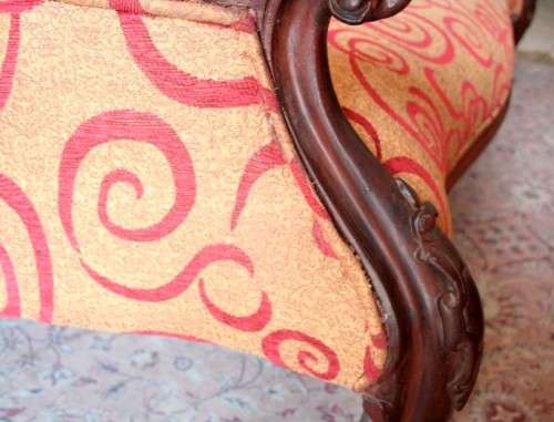 An antique Victorian  "parlour settee" couch w carved detailing and period upholstery on castors.