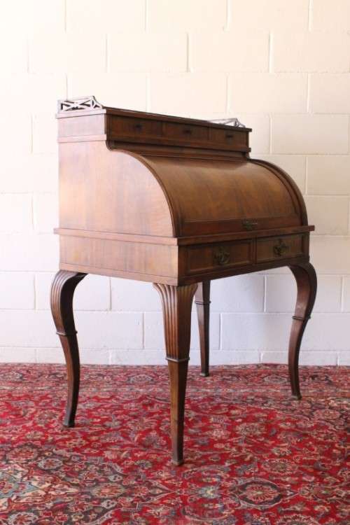 A magnificently made walnut barrel-roll top writing desk with an array of drawers and pigeon holes