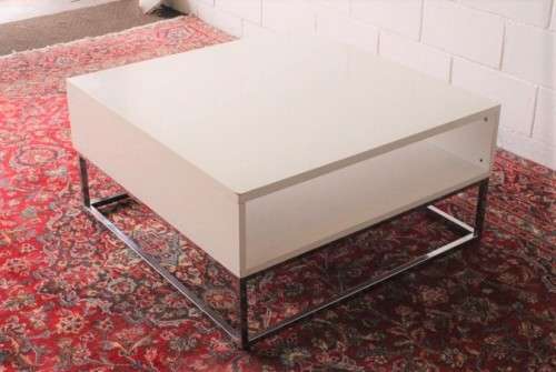 A stunning and modern white square coffee table with a magazine/ book shelf on chromed table legs