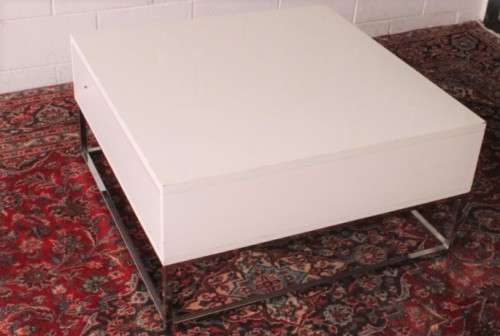 A stunning and modern white square coffee table with a magazine/ book shelf on chromed table legs