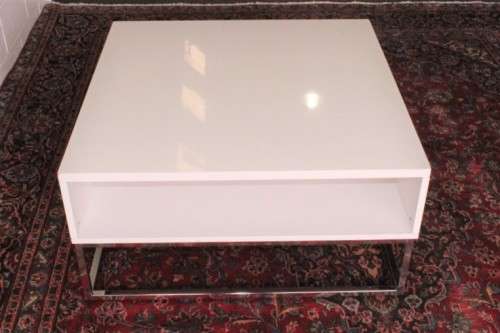 A stunning and modern white square coffee table with a magazine/ book shelf on chromed table legs
