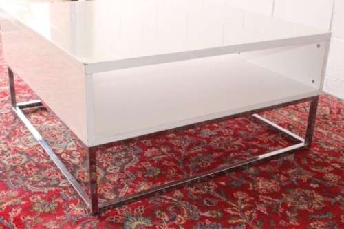 A stunning and modern white square coffee table with a magazine/ book shelf on chromed table legs