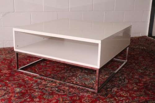 A stunning and modern white square coffee table with a magazine/ book shelf on chromed table legs